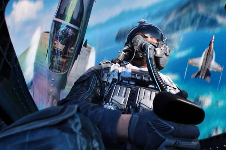 Fighter pilot wearing helmet and gear in cockpit with jet and ocean view.